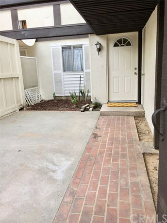 Front view of an entryway to a house with a brick walkway leading to the door.