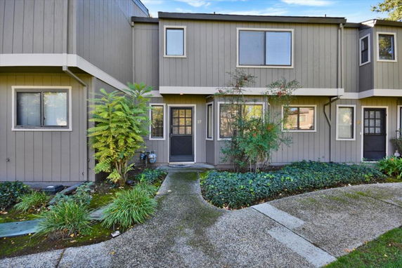 Front view of a two-story townhouse with a garden pathway.