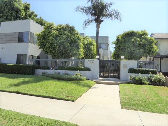 Front view of a modern two-story apartment building with a gated entrance.