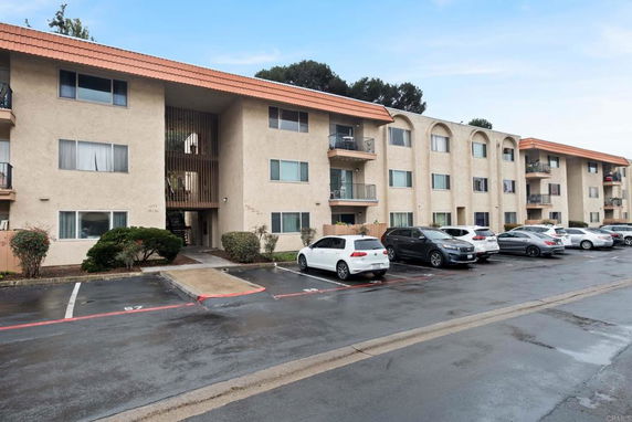 Front view of a multi-story apartment building with parking area.