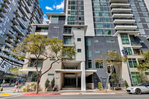 Front view of a modern high-rise building with multiple balconies and a glass facade.