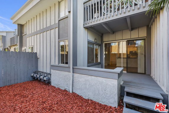 Front view of a house with a balcony and patio area.