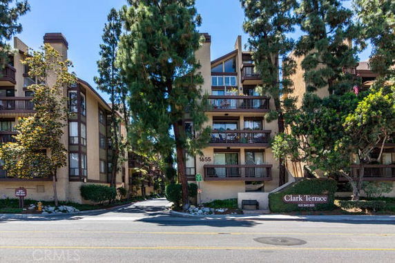 Front view of a multi-story residential building complex with balconies and trees.