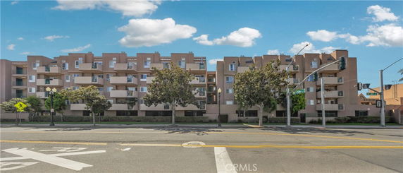 Front view of a multi-story residential building with balconies along a street.