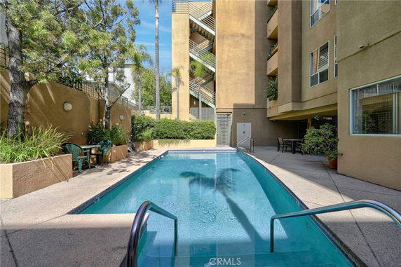 Outdoor view of a swimming pool adjacent to a multi-story building.