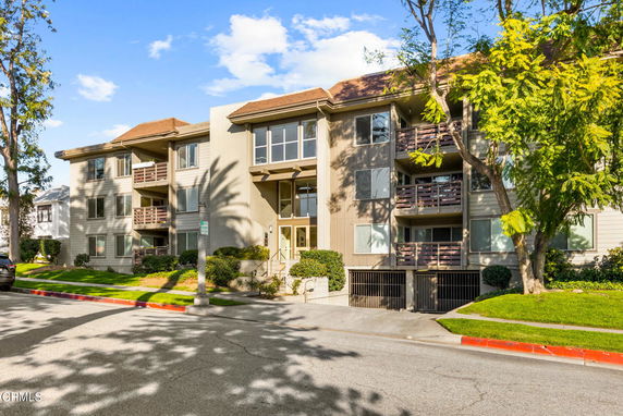 Front view of a multi-story residential building with balconies and a sloped roof.