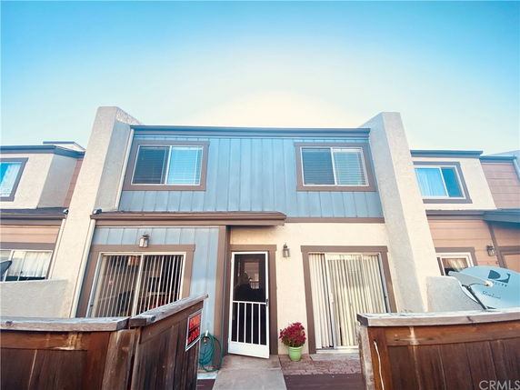 Front view of a two-story townhouse with sliding glass doors and a fenced entrance.