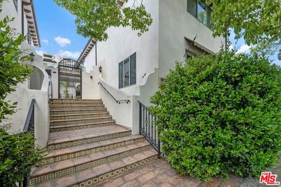 Front view of a house with exterior stairs leading to an upper entrance.