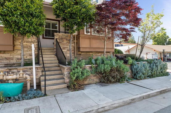 Front view of a house with stone walls and a staircase leading to the entrance.