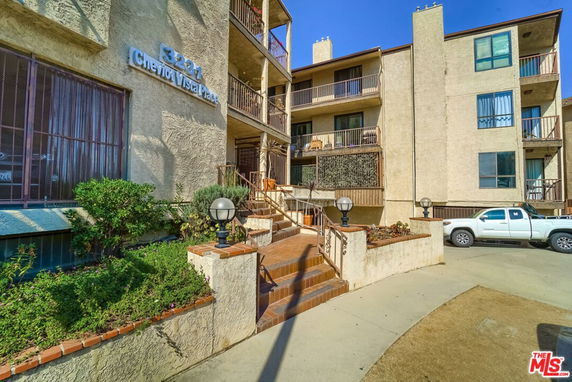 Front view of a multi-story residential building with balconies and a small entrance staircase.