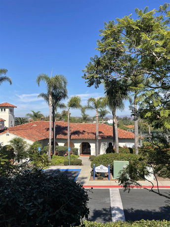 Front view of a single-story building with red tile roof and palm trees.