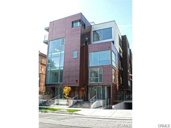 Modern multi-story building with large windows and brown exterior panels.