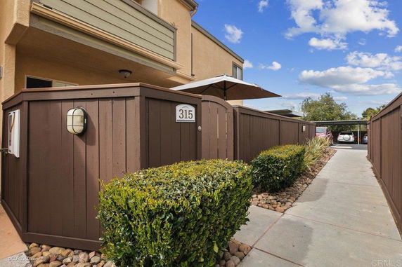 Front view of a house with fenced patio and a visible parking area.