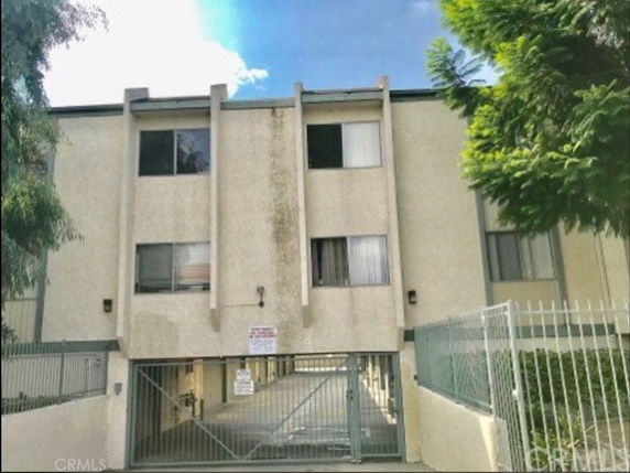 Front view of a three-story apartment building with gated entrance.