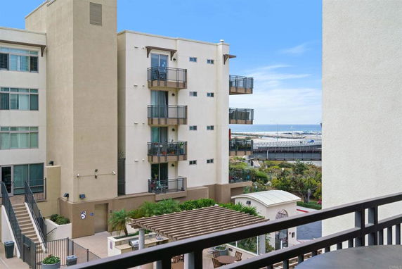 View of an apartment building with balconies and a glimpse of the ocean in the background.