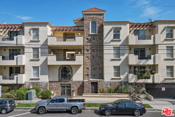 Front view of a multi-story apartment building with balconies and a central stone facade.