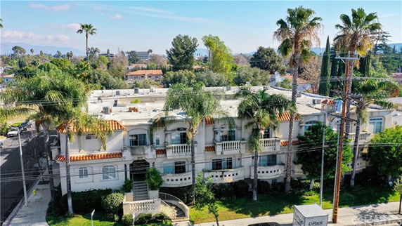 Front view of a multi-story building with balconies and palm trees in front.