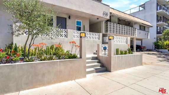 Front view of a multi-story residential building with a decorative facade and landscaped entrance.