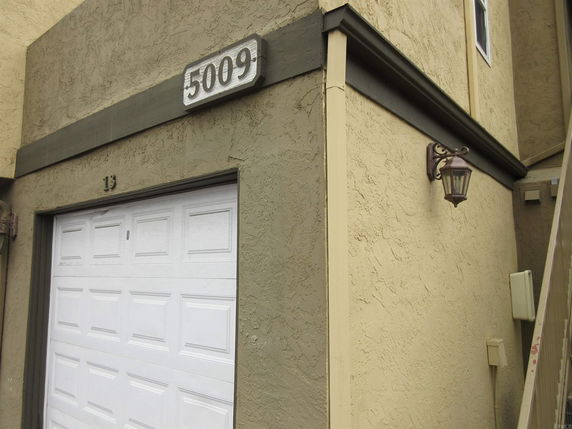 Partial view of a house facade with a garage and a wall-mounted lantern.