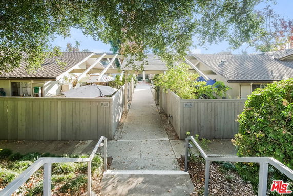 Front view of a residential structure with a sloped roof and wooden fences.