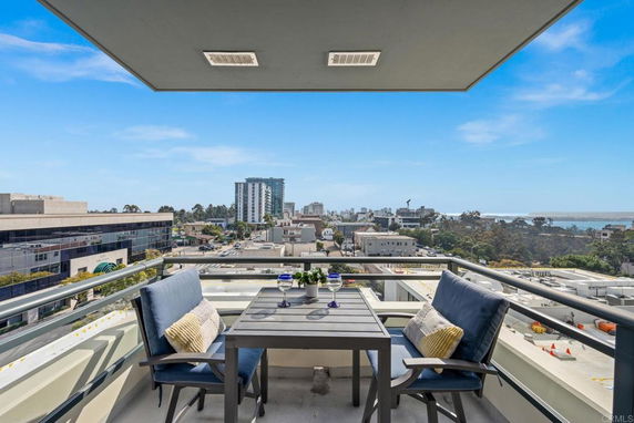 Outdoor balcony with seating and view of city buildings and coastline.