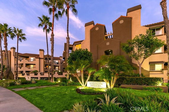 Front view of a multi-story residential building with balconies and landscaped entrance.