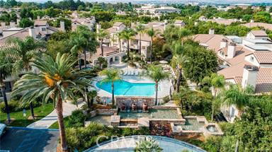Aerial view of a residential area featuring a central swimming pool surrounded by buildings and trees.
