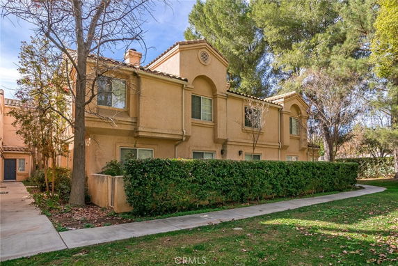 Front view of a two-story house with a tan exterior and a tile roof.