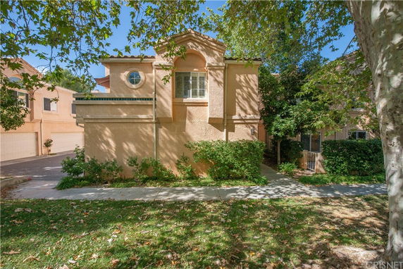 Front view of a two-story house with a stucco exterior and a circular window accent.