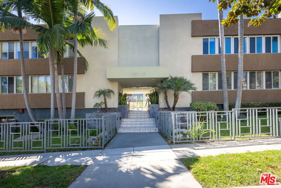Front view of a building with a central entrance and surrounding palm trees.