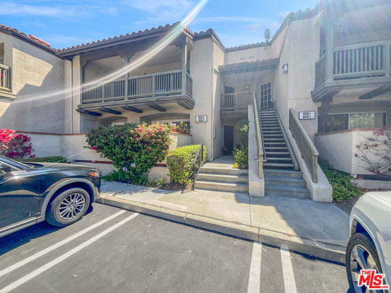 Front view of a two-story residential building with a parking area in front.