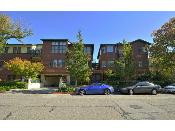 Front view of a multi-story residential building with parked cars.