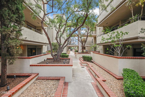 Front view of a multi-story building with balconies and landscaped pathway.