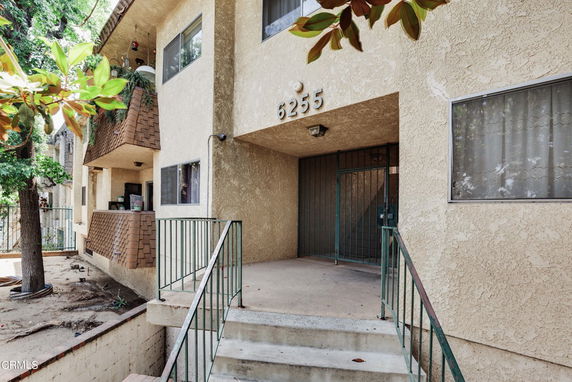Front view of a two-story building with balconies and a staircase leading to the entrance.