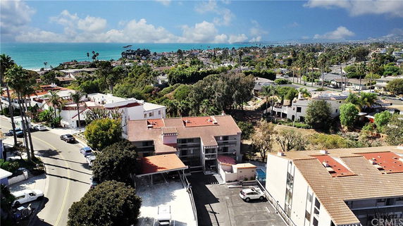 Aerial view of a coastal neighborhood with residential buildings and ocean in the background.