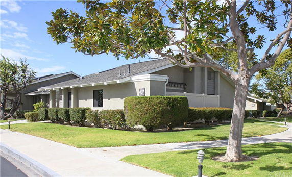 Front view of a single-story house with a sloped roof and manicured bushes.