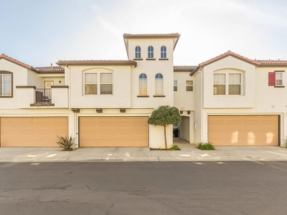 Front view of a two-story house with multiple garages and arched windows.