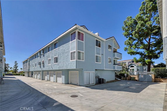 Front view of a three-story residential building with multiple garages on the ground floor.