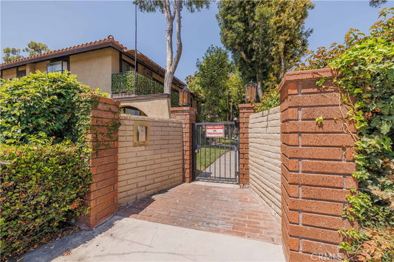 Front view of a two-story house with a gated entrance and brick walls.