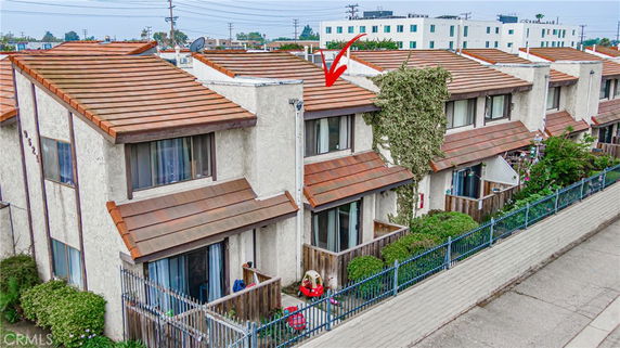 Front view of a multi-story townhouse with a sloped roof and patio areas.