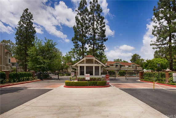 Front view of a gated community entrance with a small booth.