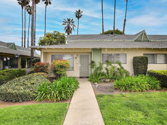 Front view of a single-story house with a walkway and plants.