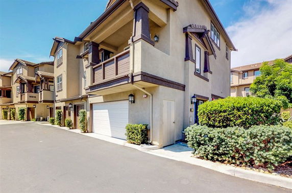 Front view of a modern multi-story townhouse with a garage and balcony.