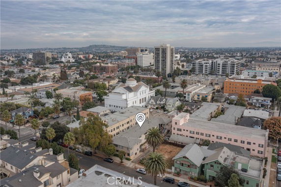 Aerial view of a cityscape featuring multiple buildings, including a large white structure and several residential buildings.