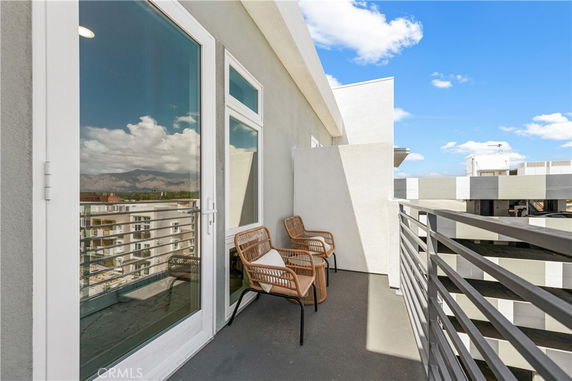 Balcony with chairs and view of surrounding cityscape and mountains.