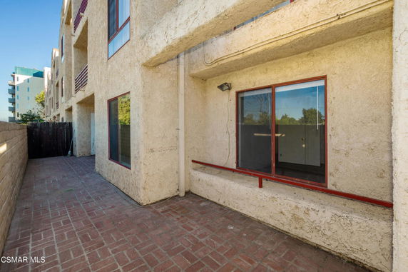 Side view of a multi-story building with beige exterior walls and red-framed windows.