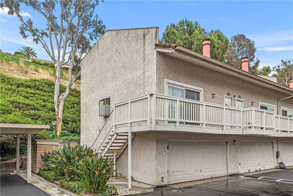 Side view of a two-story building with garages on the ground floor and balconies on the upper level.