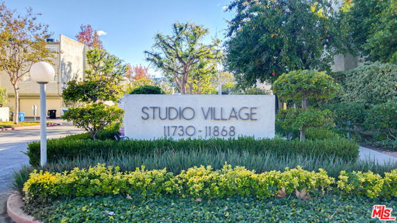 Front view of a residential complex entrance with a Studio Village sign.