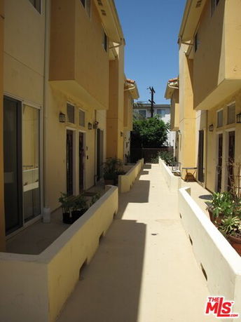 Walkway between two multi-story buildings with beige walls.