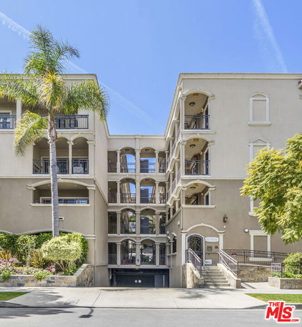 Front view of a multi-story residential building with balconies and an entrance.